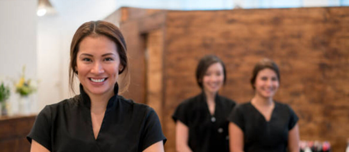 Smiling practitioners in professional treatment uniforms at a spa reception